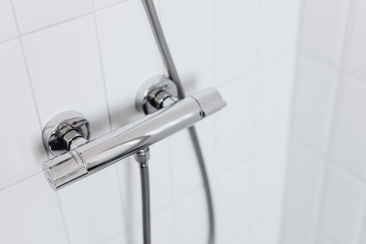 Modern chrome shower faucet on white tiled wall, elegant and clean design.